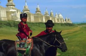 Mongolia. Bambino a cavallo e, sullo sfondo, il monastero di Erdeni-zu. De Agostini Picture Library / W. Buss